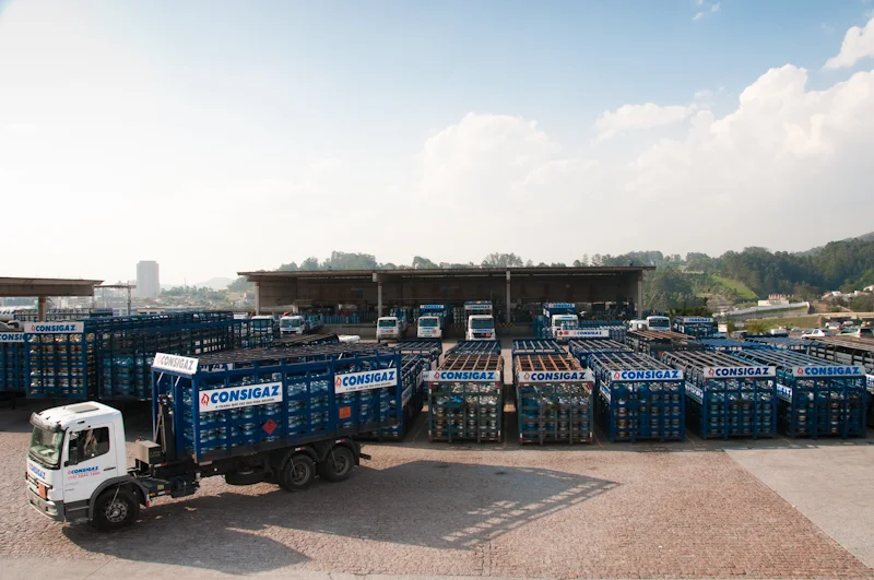 Frota de caminhões e contêineres de gás da Consigaz em pátio industrial, exemplo para conteúdo sobre manutenção de frota.